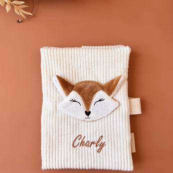 un protège carnet de santé en velours blanc avec une tête de renard et un prénom brodé